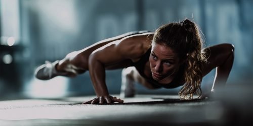 Athletic woman exercising push-ups in a health club. Copy space.